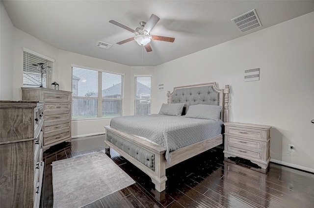 bedroom with dark wood-style floors, a ceiling fan, visible vents, and baseboards