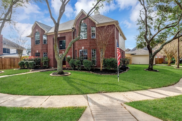 view of front of house featuring brick siding, a chimney, a front yard, and fence