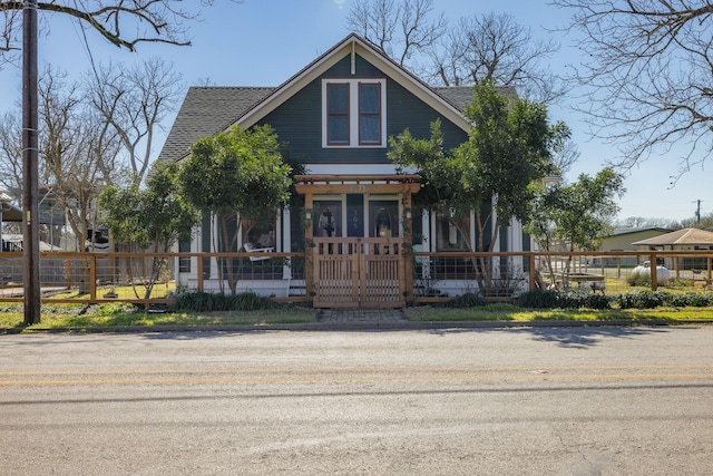 view of front of house with roof with shingles, a porch, and a fenced front yard