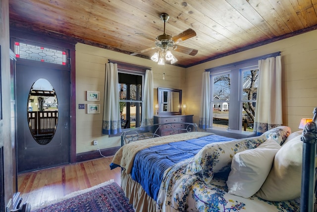 bedroom with hardwood / wood-style flooring, wood ceiling, wooden walls, and a ceiling fan