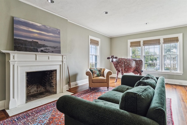 living area featuring a fireplace with flush hearth, crown molding, baseboards, and wood finished floors