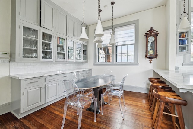 dining area with dark wood-style flooring and baseboards