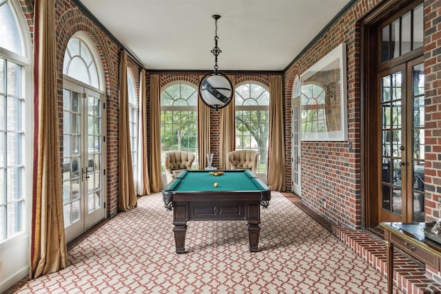 recreation room featuring brick wall, a wealth of natural light, and french doors