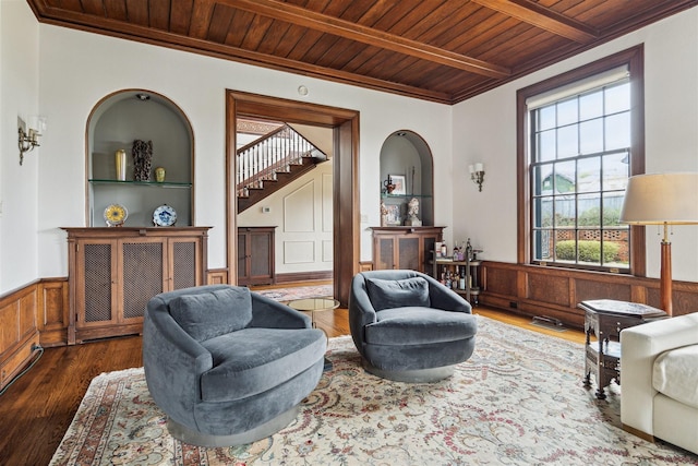 sitting room featuring wooden ceiling, ornamental molding, wainscoting, beam ceiling, and wood-type flooring