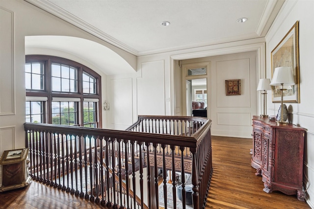 hall with ornamental molding, wood finished floors, an upstairs landing, and a decorative wall