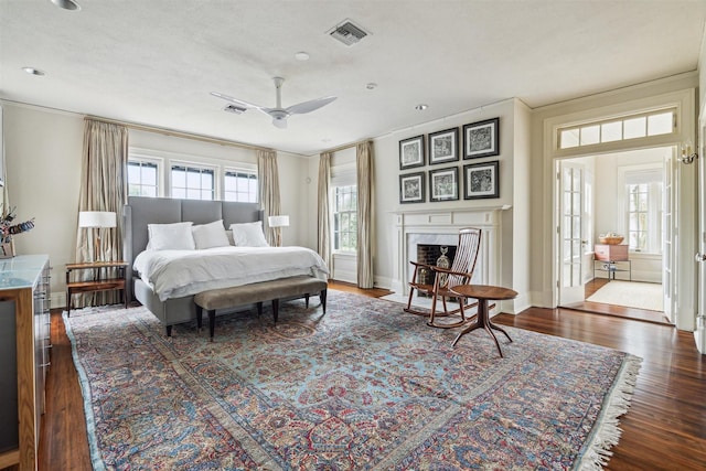 bedroom with visible vents, dark wood finished floors, baseboards, and a premium fireplace