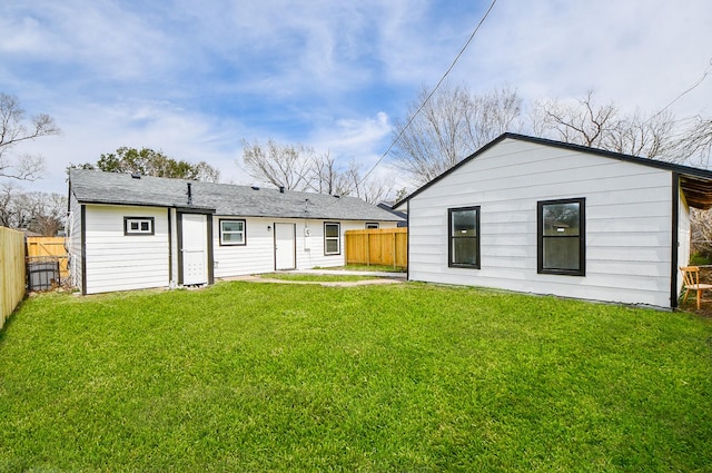 rear view of property featuring a fenced backyard and a lawn