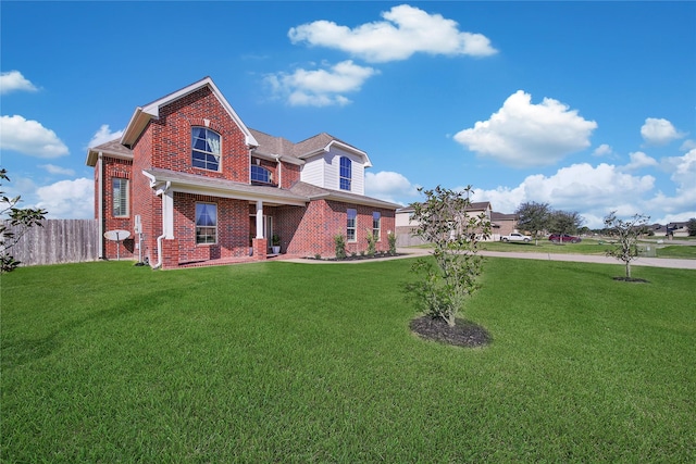 traditional home featuring brick siding, a front yard, and fence