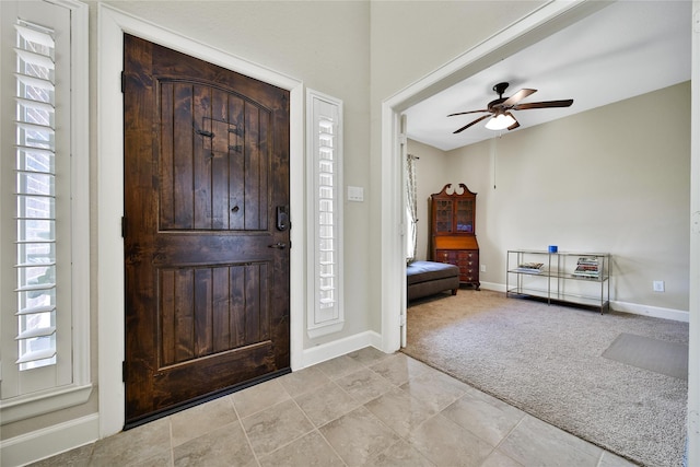 entrance foyer with light carpet, baseboards, and a ceiling fan