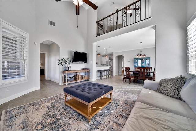 living room featuring visible vents, arched walkways, baseboards, tile patterned flooring, and ceiling fan with notable chandelier