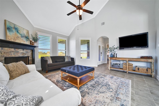 living room featuring a wealth of natural light, visible vents, arched walkways, and crown molding