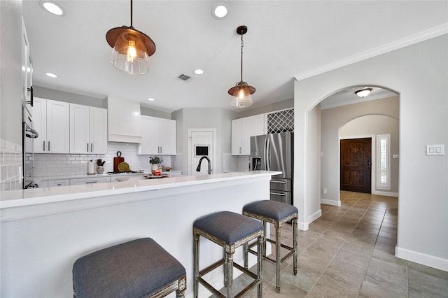 kitchen with a peninsula, visible vents, a kitchen breakfast bar, appliances with stainless steel finishes, and tasteful backsplash