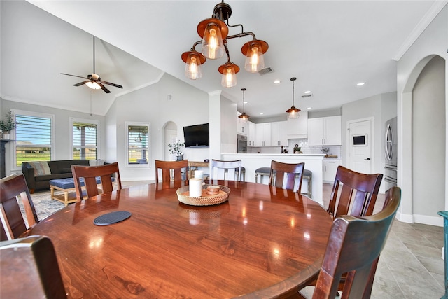 dining room with arched walkways, crown molding, lofted ceiling, visible vents, and ceiling fan with notable chandelier