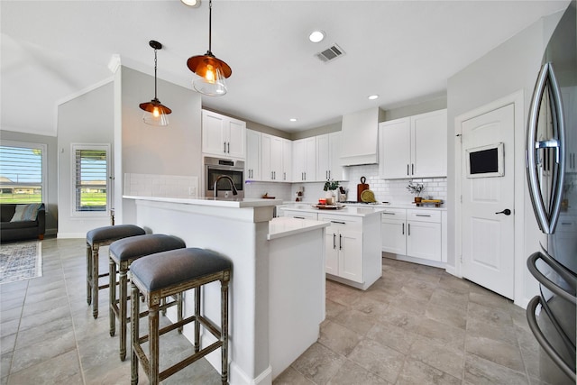 kitchen featuring stainless steel appliances, a peninsula, visible vents, custom exhaust hood, and a kitchen bar