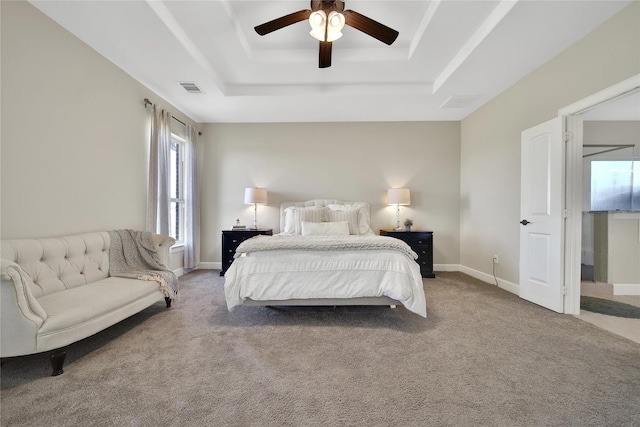 carpeted bedroom featuring a ceiling fan, a raised ceiling, visible vents, and baseboards