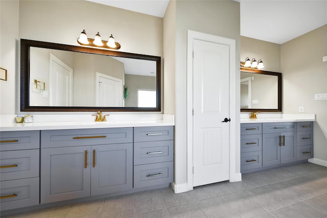 bathroom featuring two vanities, a sink, baseboards, and tile patterned floors