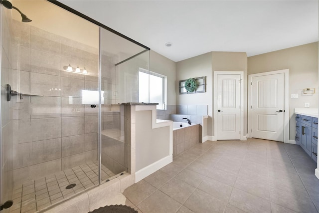 bathroom featuring tile patterned flooring, vanity, baseboards, a bath, and a stall shower