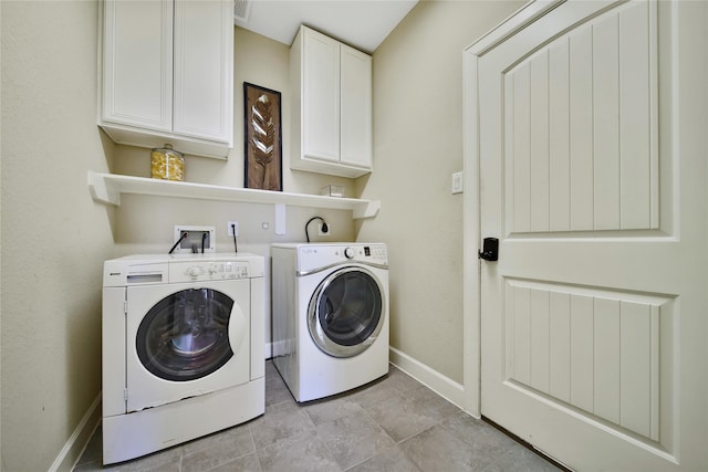 clothes washing area featuring separate washer and dryer, cabinet space, and baseboards