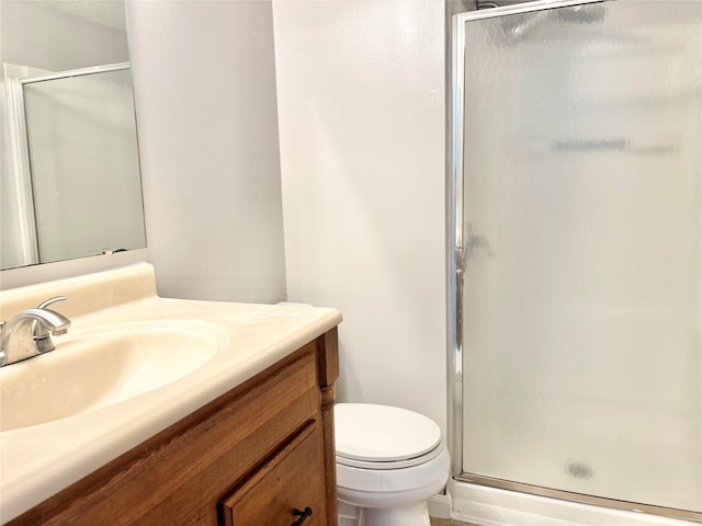 bathroom with toilet, a shower stall, and vanity