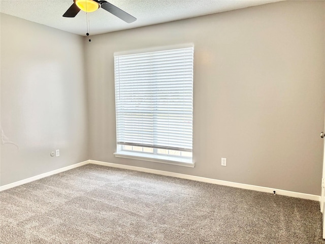 carpeted empty room featuring a textured ceiling, a ceiling fan, and baseboards