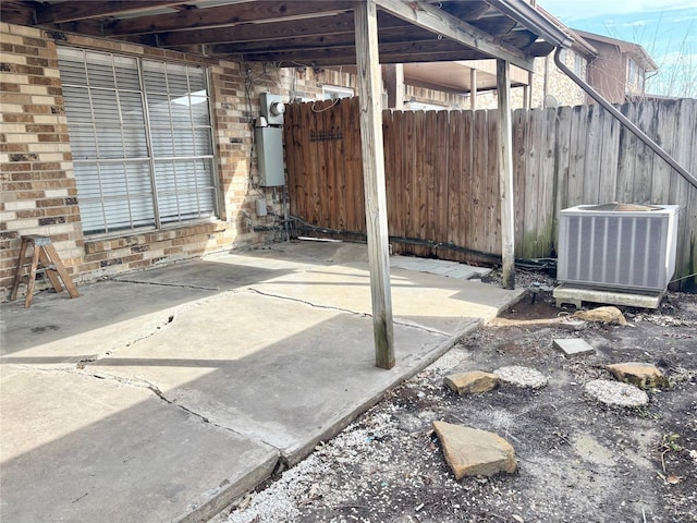 view of patio with a carport, cooling unit, water heater, and fence