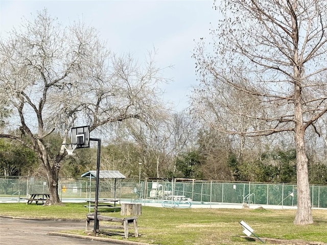 view of sport court with a lawn, a community pool, and fence