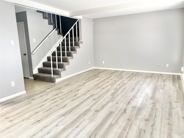 unfurnished room featuring stairs, baseboards, and wood finished floors