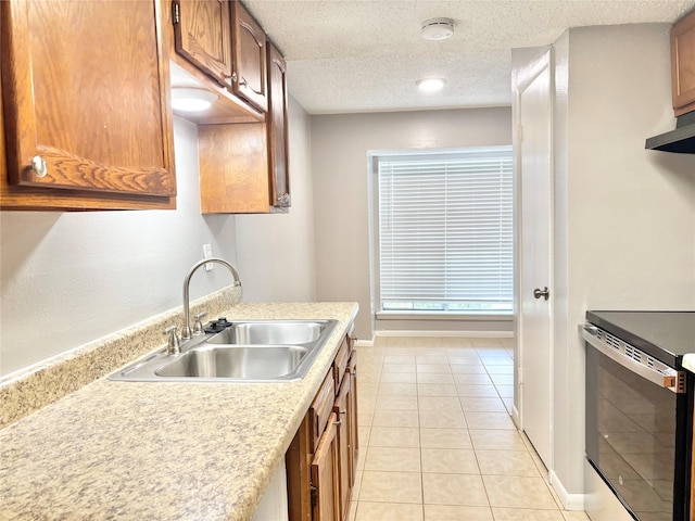 kitchen with a textured ceiling, light tile patterned flooring, a sink, electric stove, and light countertops