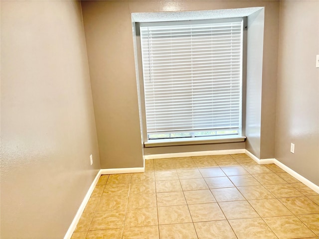 spare room with baseboards and tile patterned floors