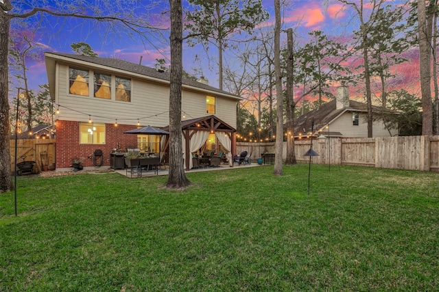 back of house featuring a patio area, a fenced backyard, a lawn, and brick siding