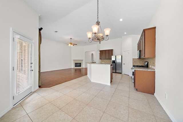 kitchen with light tile patterned floors, tasteful backsplash, appliances with stainless steel finishes, open floor plan, and ceiling fan with notable chandelier