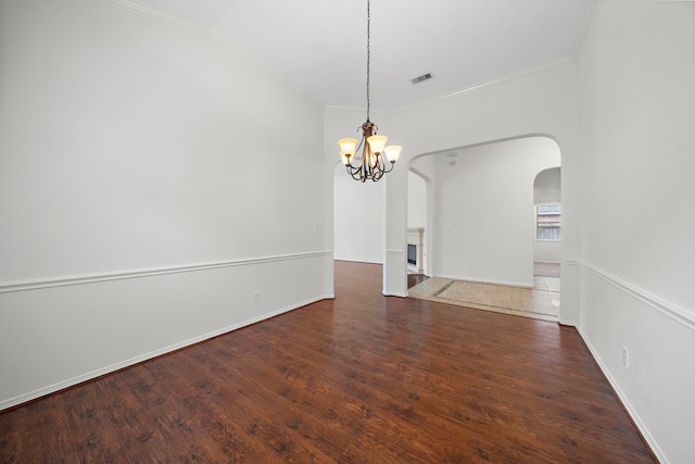 empty room with ornamental molding, arched walkways, visible vents, and wood finished floors