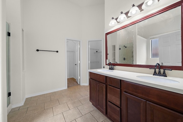 full bathroom with double vanity, a stall shower, a spacious closet, and a sink