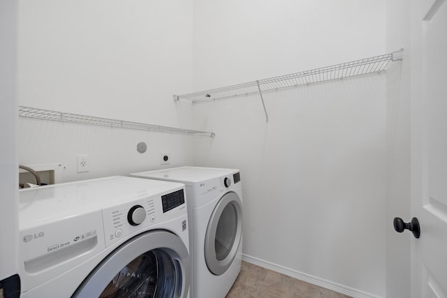 laundry area with laundry area, light tile patterned floors, baseboards, and washer and clothes dryer