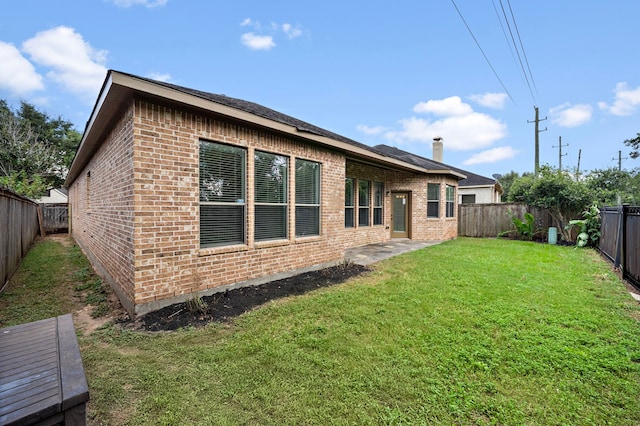 rear view of property with brick siding, a yard, and a fenced backyard