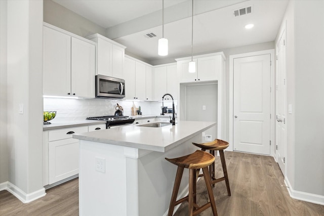 kitchen featuring appliances with stainless steel finishes, light wood-type flooring, visible vents, and a sink