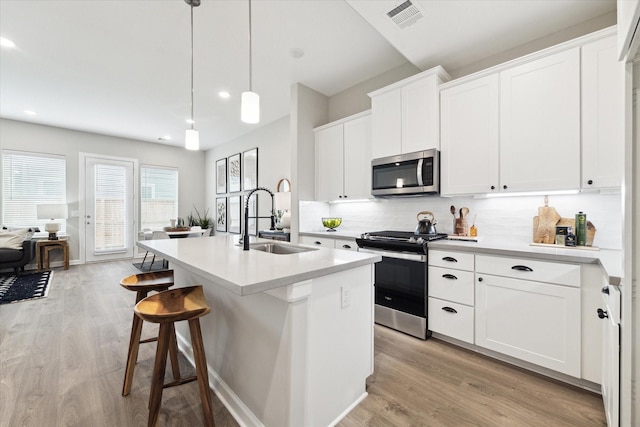 kitchen featuring light wood finished floors, visible vents, appliances with stainless steel finishes, and a sink