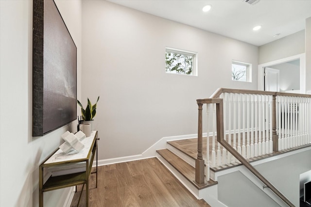 hall featuring recessed lighting, wood finished floors, visible vents, an upstairs landing, and baseboards