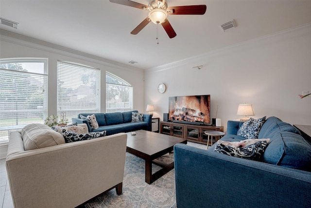 living area with visible vents, a ceiling fan, and ornamental molding