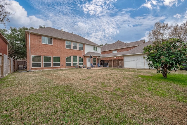 back of property featuring a garage, brick siding, a yard, and a fenced backyard