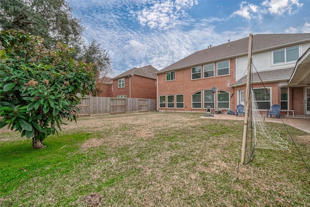 back of house featuring brick siding, fence, a lawn, and a patio