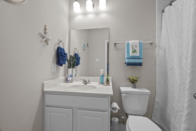 full bathroom with a textured wall, curtained shower, vanity, and toilet