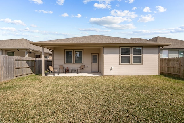 rear view of house featuring a patio area, a fenced backyard, a yard, and roof with shingles