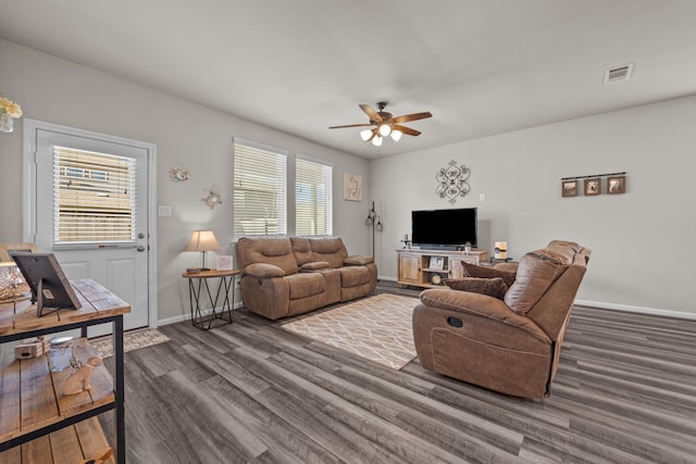 living room featuring a ceiling fan, visible vents, baseboards, and wood finished floors