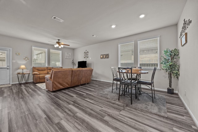 living area featuring a ceiling fan, baseboards, visible vents, and wood finished floors