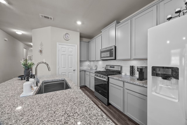 kitchen with visible vents, decorative backsplash, dark wood finished floors, appliances with stainless steel finishes, and a sink