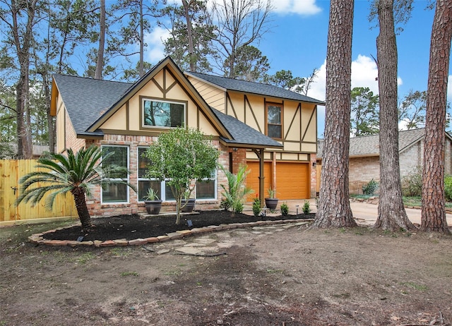 tudor home with a garage, driveway, stucco siding, roof with shingles, and brick siding