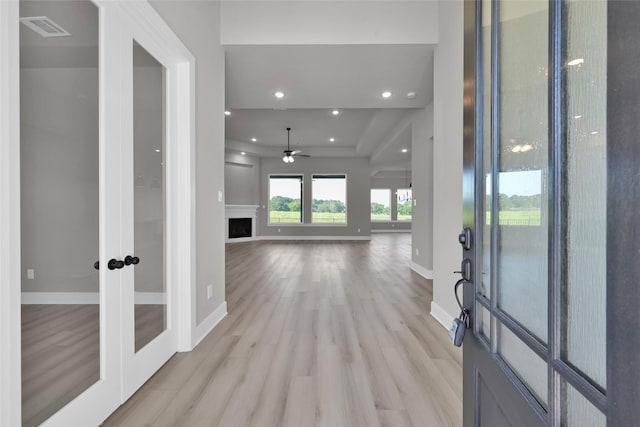 entryway with visible vents, baseboards, light wood-style flooring, french doors, and a fireplace