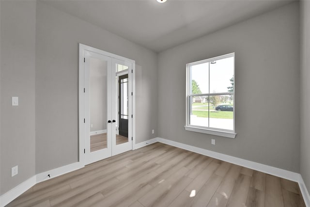 unfurnished bedroom featuring french doors, baseboards, and wood finished floors