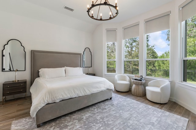 bedroom featuring multiple windows, wood finished floors, visible vents, and a notable chandelier